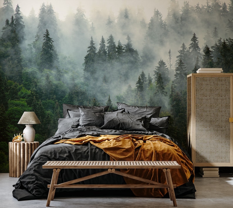 May include: A bedroom scene featuring a forest mural, a bed with dark gray bedding and an orange throw blanket. A wooden bench sits at the foot of the bed. A wooden side table with a lamp and a woven cabinet complete the room's decor.