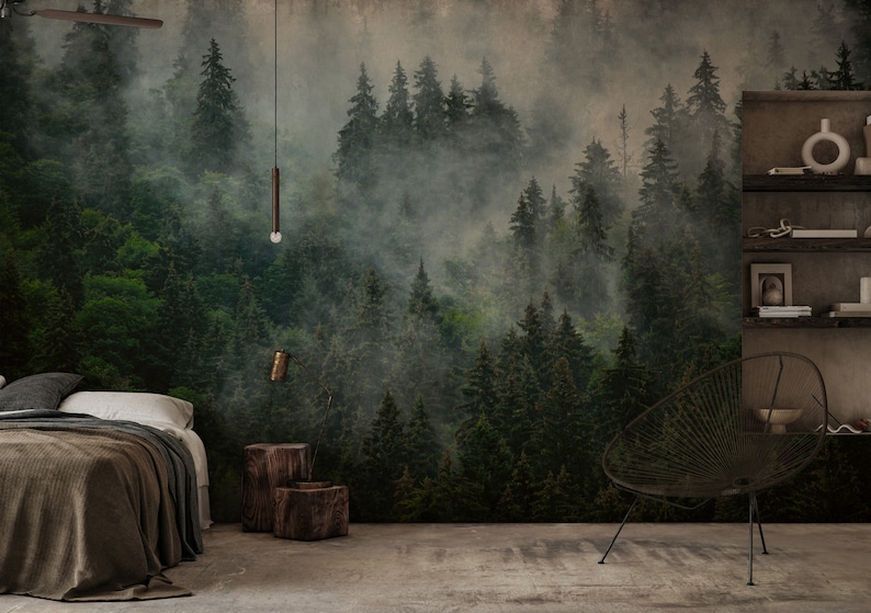 May include: A forest-themed mural dominates the wall, depicting a misty, green forest with tall trees. The room features a bed with a brown blanket, wooden stools, and a modern chair. A shelf displays decorative items.