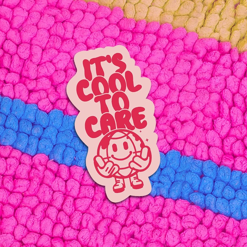 Pink and blue sticker with the text "It's Cool To Care" in red letters. A cartoon earth with a smiling face and arms is holding up peace signs.