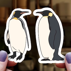 May include: Two penguin stickers, one black and white and one yellow and white, with a white outline.