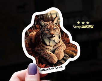 May include: A sticker featuring a realistic illustration of a Canadian lynx with brown and white fur, sitting in a forest setting. The sticker has the text "CANADIAN LYNX" at the bottom and "Savage UNIKORN" at the top.