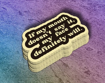 May include: A stack of stickers with a cream-colored background and black text that reads, "If my mouth doesn't say it, my face definitely will." The stickers have a rounded rectangle shape and are stacked on a purple and blue textured surface.