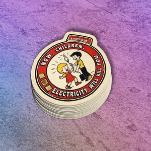 May include: A stack of round stickers with a vintage illustration. The stickers feature a red and white circular design with the text "NOW CHILDREN: ELECTRICITY WILL KILL YOU" and a cartoon of two children. The top of the sticker reads "SAFETY CLUB".