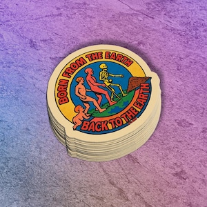 May include: A stack of round stickers with a colorful design. The stickers feature the text "BORN FROM THE EARTH BACK TO THE EARTH" around a central image of figures and a skeleton. The figures are in red, orange, and yellow.