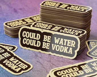 May include: A stack of rectangular stickers with rounded, scalloped edges. The stickers feature a dark brown background with cream-colored text that reads "COULD BE WATER COULD BE VODKA" in a bold, sans-serif font. The design is repeated on each sticker.