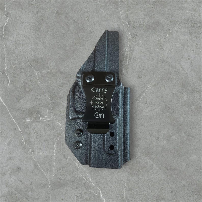 K&ouml;nnte beinhalten: Eine schwarze Holster mit einem Clip, mit dem Text "Carry" und "Gayle Force Tactical". Das Holster ist f&uuml;r eine Schusswaffe konzipiert. Auf dem Clip steht das Wort "On".
