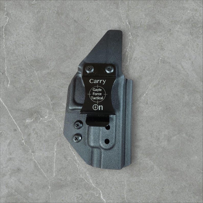 K&ouml;nnte beinhalten: Eine schwarze Polymerholster mit Metallclip. Der Clip tr&auml;gt die Aufschrift "Carry", "Gayle Force Tactical" und das Wort "On". Konzipiert f&uuml;r das Tragen am K&ouml;rper, ist es ein praktisches Zubeh&ouml;r.