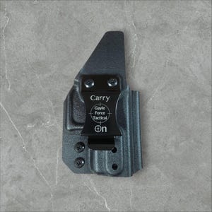 K&ouml;nnte beinhalten: Eine schwarze Holster mit einem Metallclip. Auf der Holster stehen die W&ouml;rter "Carry" und "Gayle Force Tactical". Die Holster ist zum Tragen am K&ouml;rper konzipiert.