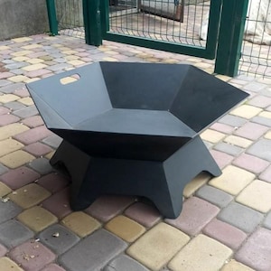 Può includere: Un braciere nero e geometrico con una vasca esagonale e una base robusta. Il braciere ha una maniglia ritagliata su un lato. Il braciere è in metallo ed è progettato per l'uso all'aperto.