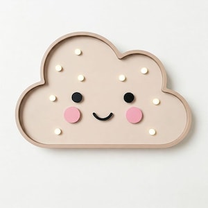 Peut inclure: Une décoration murale en bois en forme de nuage de couleur rose clair avec un visage souriant, des yeux noirs et des joues roses. Le nuage a des points blancs autour des bords.