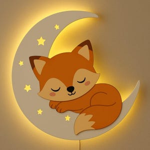 May include: A whimsical wall decor piece featuring a sleeping fox on a crescent moon. The fox is orange and cream, with closed eyes, resting on a white moon with yellow stars. The moon has a warm, yellow glow, creating a soft, inviting ambiance.