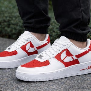 May include: White and red athletic shoes with a low-top design. The shoes feature a red toe box and a red swoosh logo on the side. The word "AIR" is printed in red on the side of the white sole.
