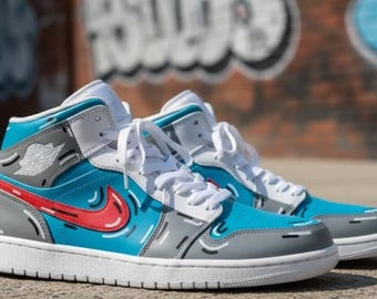May include: A pair of high-top sneakers in a vibrant color scheme. The shoes feature a combination of blue, gray, red, and white. The design includes a red swoosh, white laces, and a gray and white sole. The sneakers have a unique, artistic style.