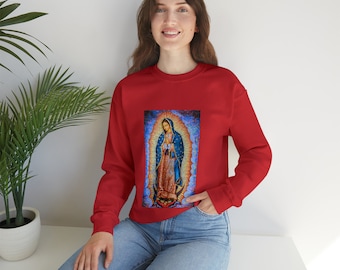 May include: A red long-sleeve sweatshirt featuring a central graphic print of the Virgin of Guadalupe. The artwork depicts the figure in a blue mantle with gold stars and a pink robe, surrounded by a radiant golden aura and a crescent moon base.