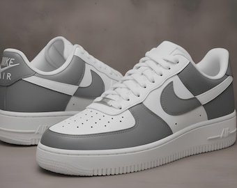 May include: White and gray Air Force 1 sneakers. The shoes feature a white base with gray accents on the toe, heel, and Nike swoosh. The sole is white, and the laces are white.