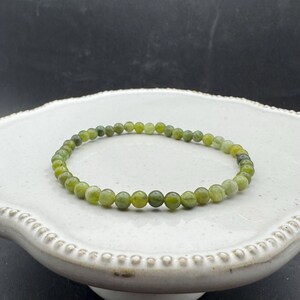 May include: A green jade stone bracelet with small round beads.