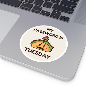 May include: A round sticker with a white background and a brown circle in the center. The brown circle has the text "MY PASSWORD IS" in brown text and a cartoon taco with a sombrero and a mustache. The text "TUESDAY" is below the taco in brown text.