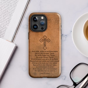 May include: A brown leather iPhone case with a cross design and a quote in a foreign language. The quote reads: "Our Father, who art in heaven, hallowed be thy name. Thy kingdom come, thy will be done, on earth as it is in heaven. Give us this day our daily bread. And forgive us our debts, as we also have forgiven our debtors. And lead us not into temptation, but deliver us from evil. Amen."