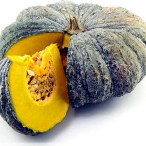 Puede incluir: Una calabaza verde y gris con un interior amarillo. La calabaza está cortada por la mitad, revelando las semillas y la pulpa.