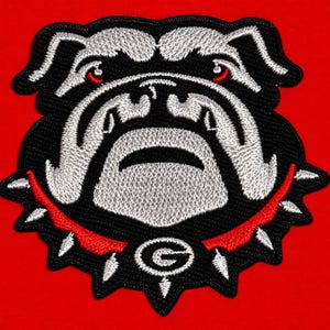 May include: An embroidered patch featuring the head of a bulldog with silver and black thread details. The bulldog wears a red spiked collar with a central silver letter G emblem. The design is set against a solid, vibrant red background.