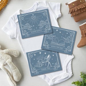 May include: Baby shower theme with blue cards, a white onesie, and brown boots. The cards have text that reads "Diaper Raffle", "Books for Baby", and "Thank You". A stuffed bunny is also in the image.