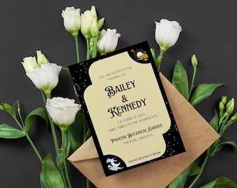 May include: Wedding invitation featuring the names "Bailey & Kennedy" with event details. The invitation has a black border with a starry design and a cream-colored center. The invitation is placed on a brown envelope, surrounded by white flowers and green leaves.
