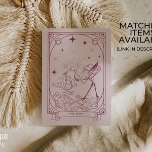 May include: A mauve-colored print featuring a stork carrying a baby, with the text "THE BABY" on a banner. The print has an art deco style with stars and decorative borders. Text on the print says "MATCHING ITEMS AVAILABLE (LINK IN DESCRIPTION)".