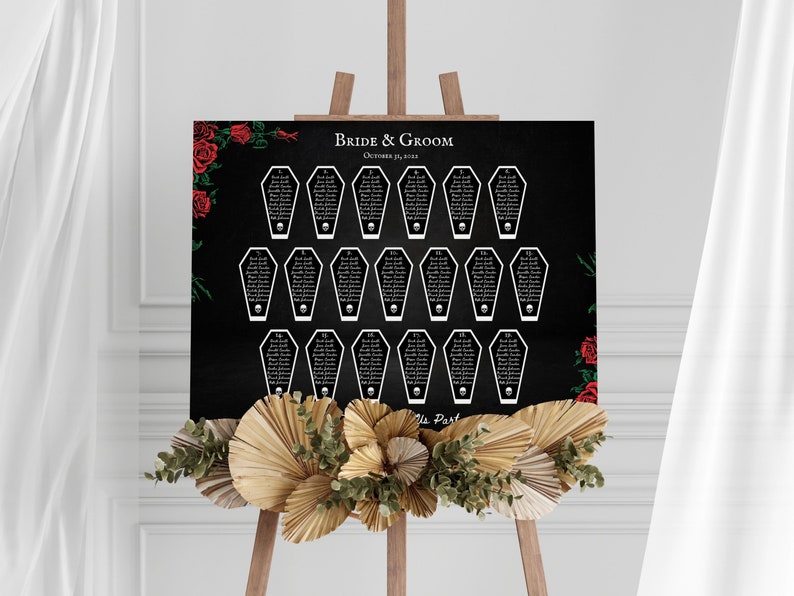 Puede incluir: Un plano de asientos de boda negro con asignaciones de mesa en forma de ata&uacute;d blanco, cada una con una calavera. Las palabras "Bride & Groom" y la fecha est&aacute;n en la parte superior. Rosas rojas y vegetaci&oacute;n decoran las esquinas.