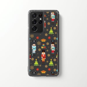 Puede incluir: Una funda transparente para teléfono con fondo negro y un patrón repetido de soldados cascanueces, árboles de Navidad y regalos. La funda está diseñada para un Samsung Galaxy S22 Ultra.