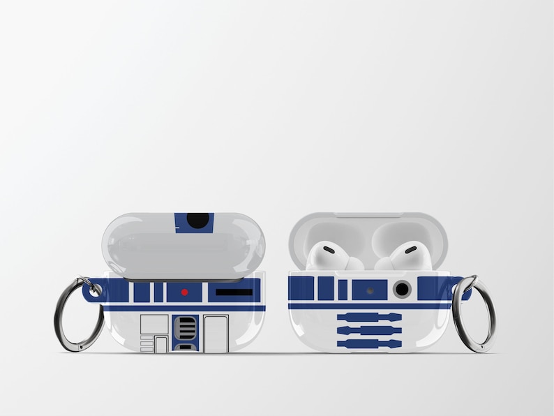 May include: White and blue protective case for wireless earbuds, featuring a design inspired by a droid. The case is shown open and closed, with a silver carabiner clip attached. The design includes rectangular and circular details.