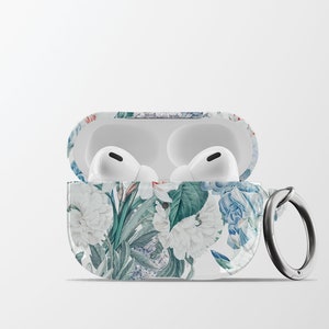 May include: A white floral patterned case for AirPods with a silver ring attached. The case is open and the white AirPods are visible inside.