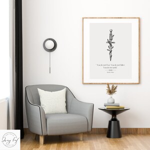 May include: A black and white illustration of a sword with vines wrapped around it. The quote "You do not fear. You do not falter. You do not yield." by Sarah J. Maas is printed below the sword. The illustration is framed and hanging on a white wall.
