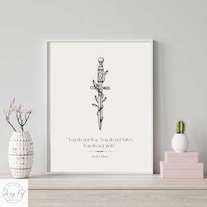 May include: A black and white illustration of a dagger with vines wrapped around it. The quote "You do not fear. You do not falter. You do not yield." is printed below the image, attributed to Sarah J. Maas.