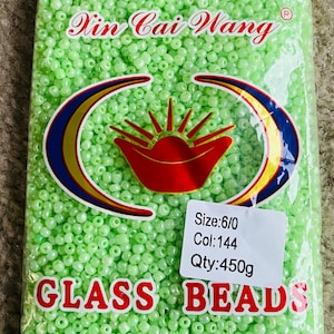 May include: A bag of 6/0 size, light green glass beads. The bag contains 144 beads and weighs 450 grams. The bag has a label that says "Xin Cai Wang" and "GLASS BEADS" with the text "MADE IN CHINA" at the bottom.