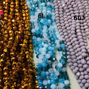 May include: Three strands of faceted glass beads. The beads are in shades of brown, blue, and grey. The strands are labelled "6s", "6t", and "6u".