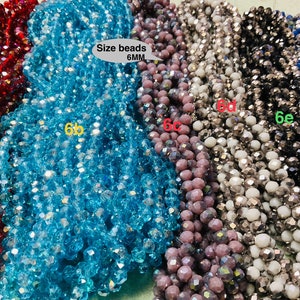 May include: Six strands of faceted glass beads, each strand a different colour: red, blue, light blue, purple, silver, and black. The beads are 6mm in size and are arranged in a row. The text "Size beads 6MM" is printed on a white label.