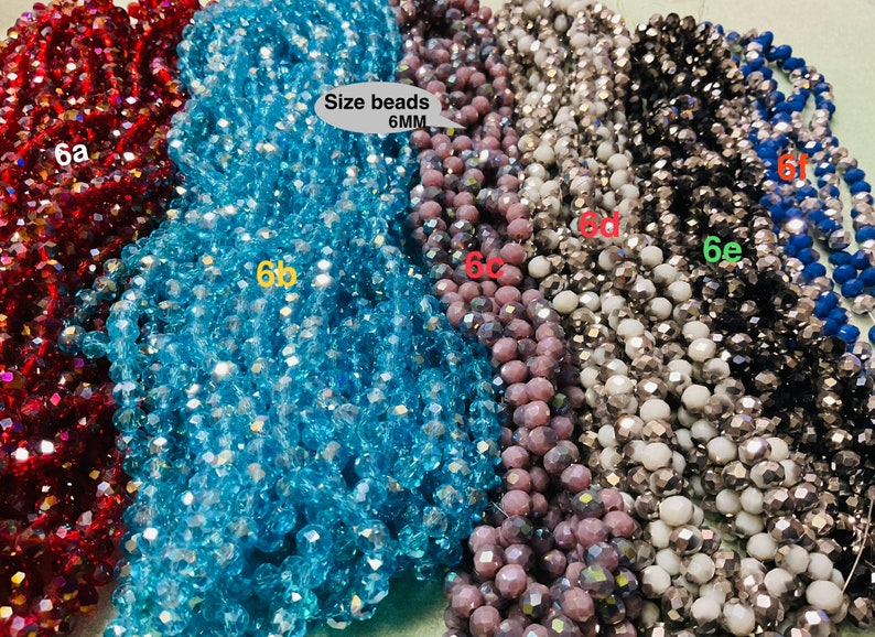 May include: Six strands of faceted glass beads, each strand a different colour: red, blue, light blue, purple, silver, and black. The beads are 6mm in size and are arranged in a row. The text "Size beads 6MM" is printed on a white label.