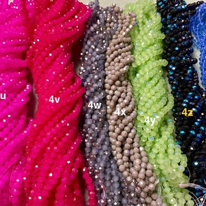 May include: Assortment of 10 strands of faceted glass beads in various colours, including pink, grey, green, blue, and black. The strands are labelled with the letters "4u", "4v", "4w", "4x", "4y", "4z", and "4za".