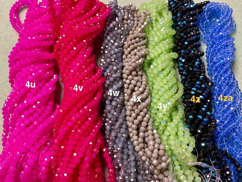 May include: Assortment of 10 strands of faceted glass beads in various colours, including pink, grey, green, blue, and black. The strands are labelled with the letters "4u", "4v", "4w", "4x", "4y", "4z", and "4za".
