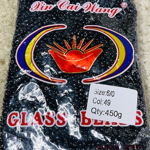May include: A bag of black glass beads, labelled "Vin Cai Wang" with a red and yellow logo. The label also states "Size: 6/0 Col: 49 Qty: 450g".