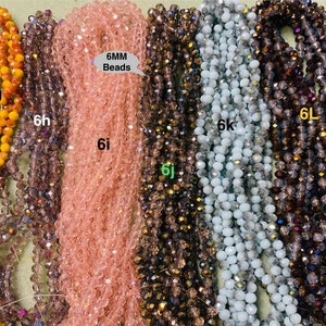 May include: Six strands of 6mm glass beads in various colours, including orange, purple, pink, brown, blue, and grey. The beads are all round and have a slight sparkle to them. The text "6MM Beads" is written on a white label.