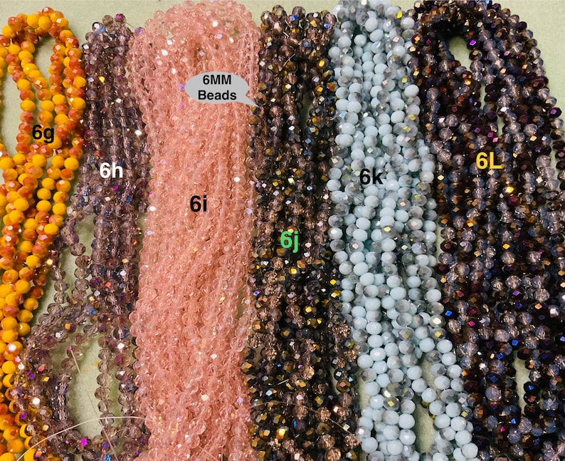 May include: Six strands of 6mm glass beads in various colours, including orange, purple, pink, brown, blue, and grey. The beads are all round and have a slight sparkle to them. The text "6MM Beads" is written on a white label.