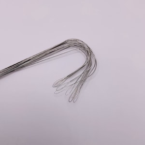 Puede incluir: Un conjunto de ganchos de metal de color plateado con un bucle en el extremo de cada gancho.