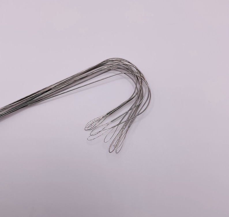 Puede incluir: Un conjunto de ganchos de metal de color plateado con un bucle en el extremo de cada gancho.