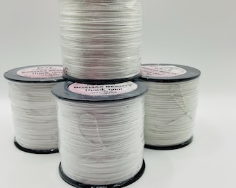 Puede incluir: Cuatro carretes de hilo blanco, cada uno envuelto en plástico negro con una etiqueta rosa que dice "Bosmax Beauty Thank you".