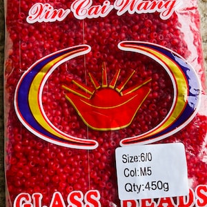 May include: A bag of red glass beads labelled "Ain Cai Wany" with the details "Size: 6/0, Col: M5, Qty: 450g" and the words "GLASS DEALS".