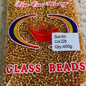 May include: A bag of gold glass beads, labelled "Glass Beads" with the brand name "Yin Cai Wang" and the details "Size: 6/0, Col: 22b, Qty: 450g".