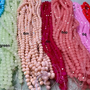 May include: Assortment of faceted glass beads in various colours, including light blue, green, pink, red, and white. The beads are strung on a string and are approximately 6mm in size.