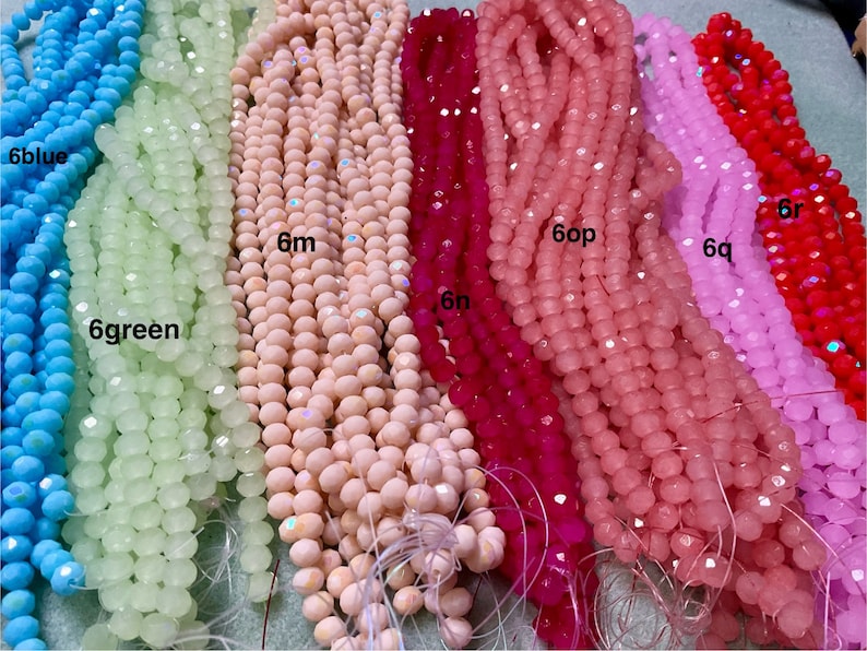 May include: Assortment of faceted glass beads in various colours, including light blue, green, pink, red, and white. The beads are strung on a string and are approximately 6mm in size.