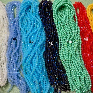May include: Assortment of 10 strands of crystal beads in various colours, including white, light blue, turquoise, dark blue, green, red, and yellow. Each strand is labelled with a letter and number, such as 4h, 4i, 4k, 4L, 4m, 4n, and 4o.